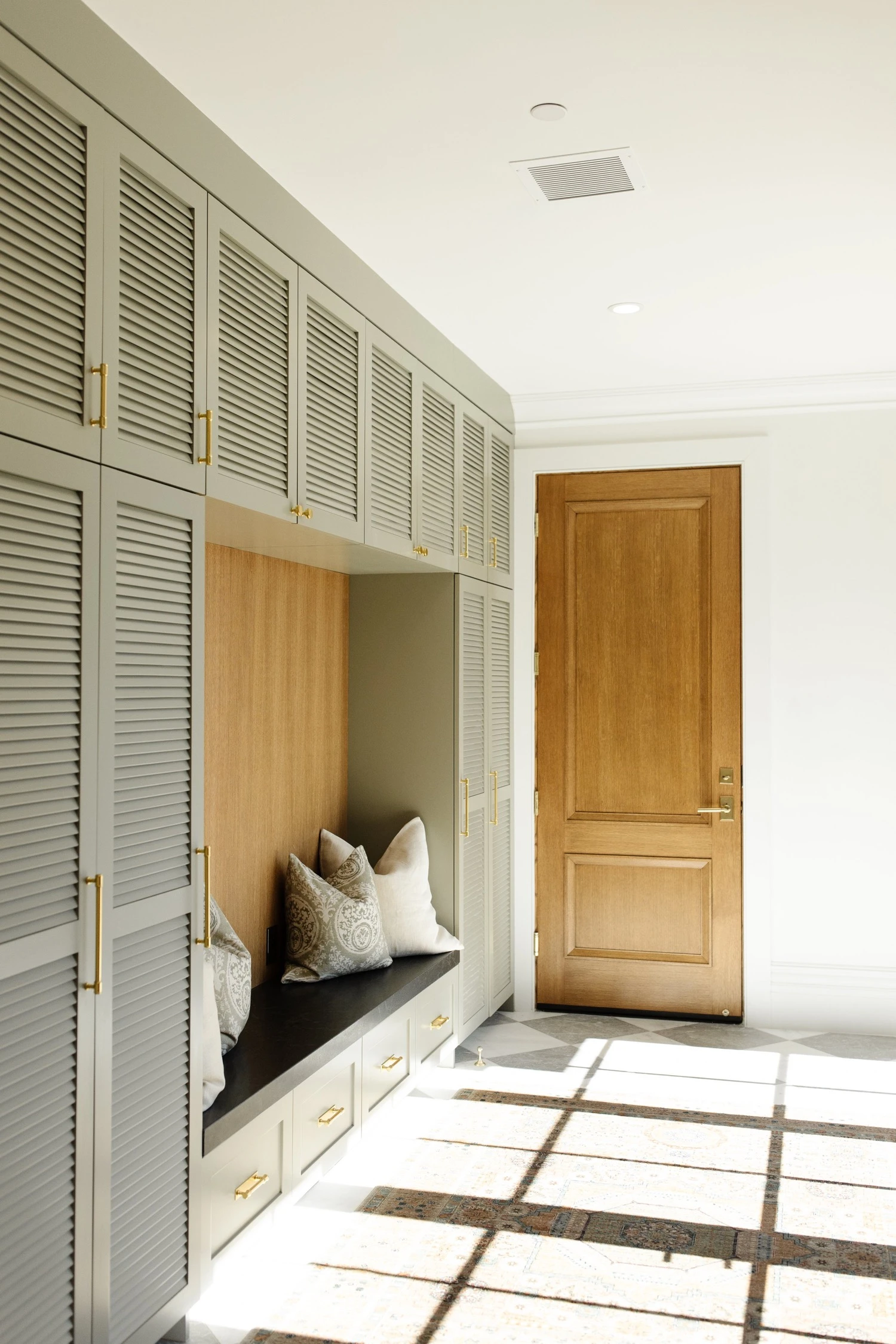 Louvered white oak built-ins with a window bench by Warner Cabinets