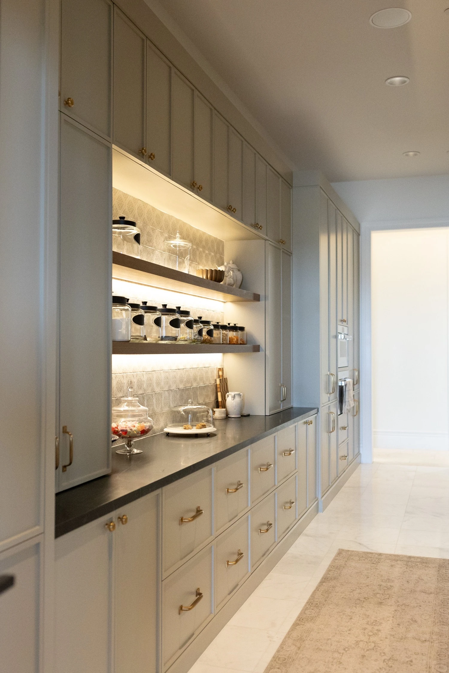 Scullery with dark cabinetry and lit open shelving by Warner Cabinets
