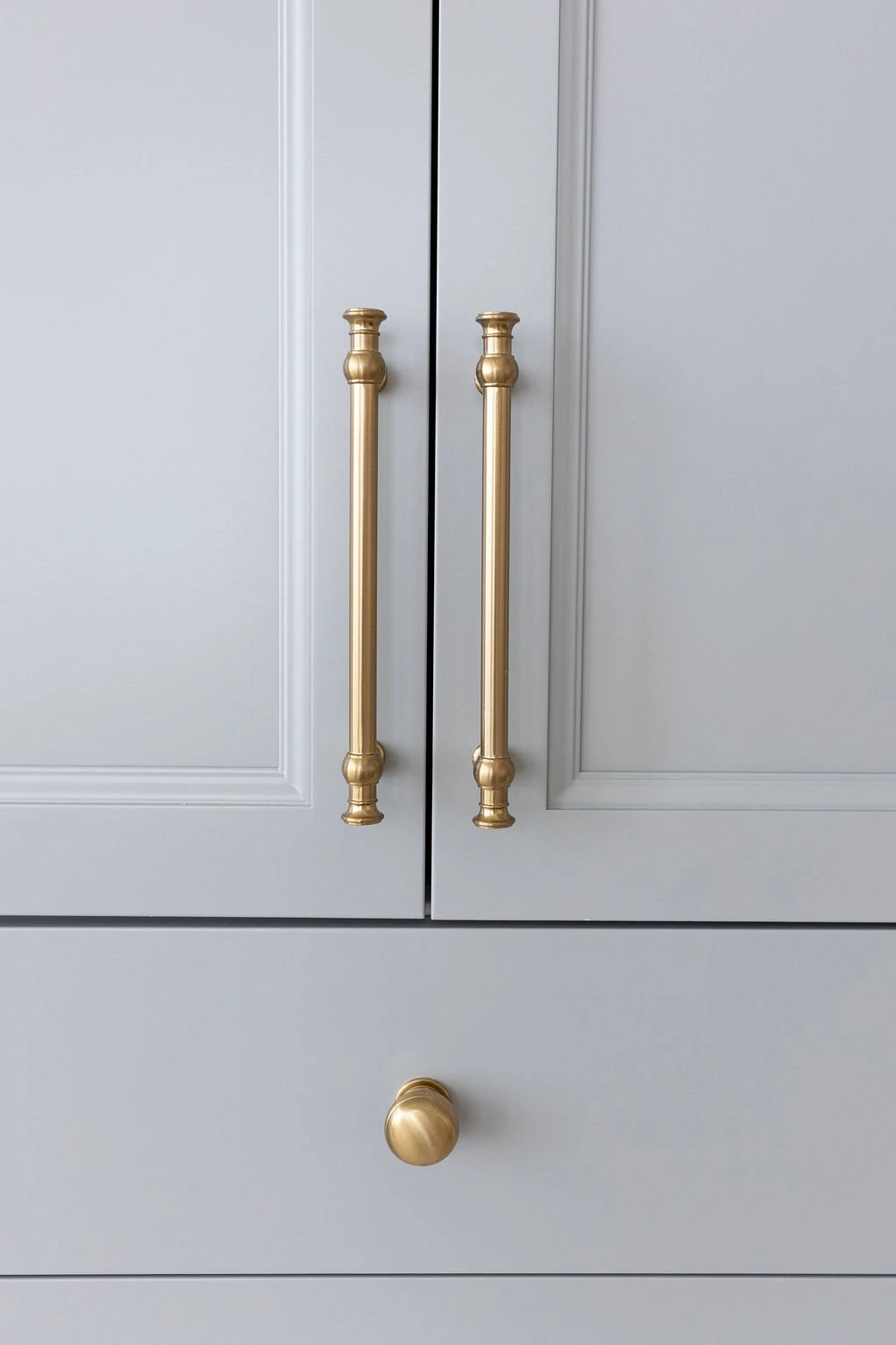 Unlacquered brass pulls on blue-gray cabinet doors, hardware detail by Warner Cabinets