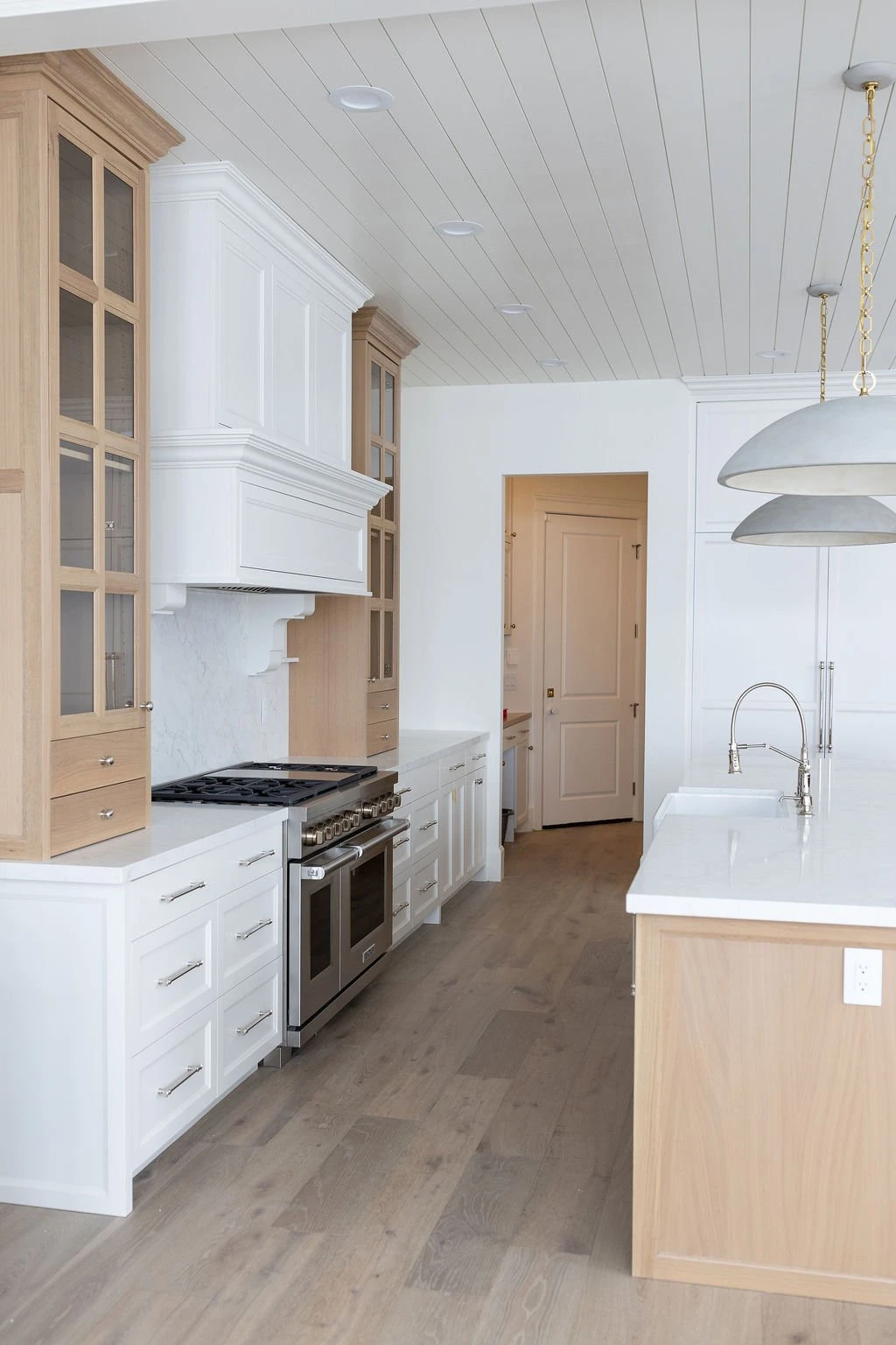 White oak glass-front uppers and paneled hood, custom kitchen cabinetry by Warner Cabinets, Traverse Mountain